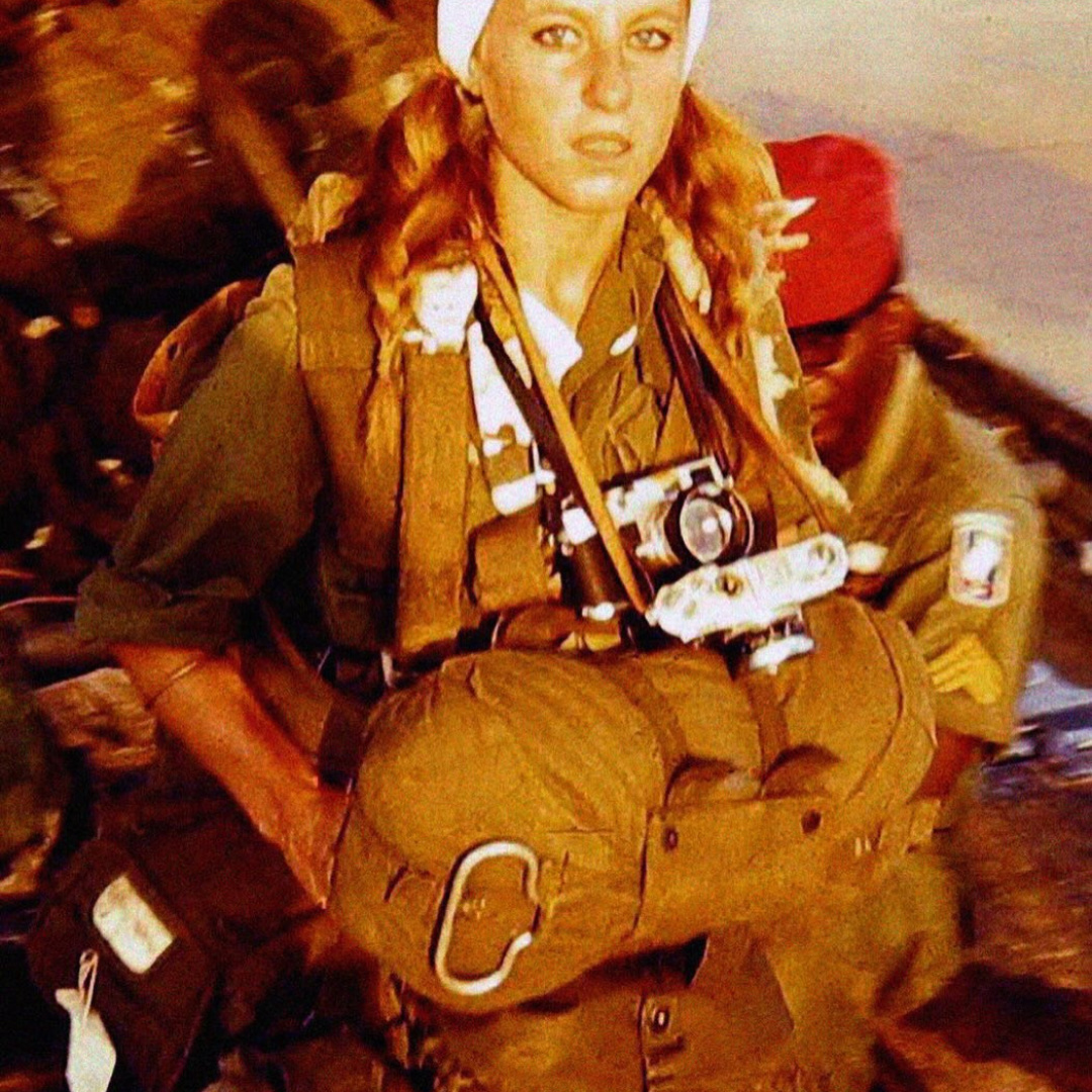 A military personnel with a camera and gear.